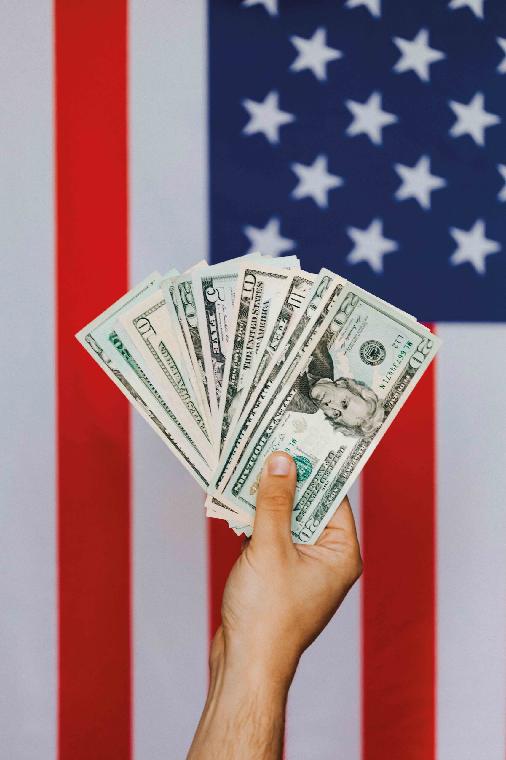 Dollar gewechselt für USA SChüleraustausch. Eine Hand mit Dollarscheinen vor der amerikanisches Flagge.