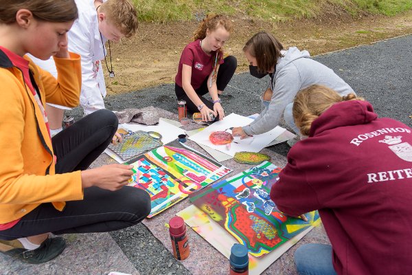 Jugendliche beim 54. Jugendwettbewerb zeichnen und malen auf dem Boden.